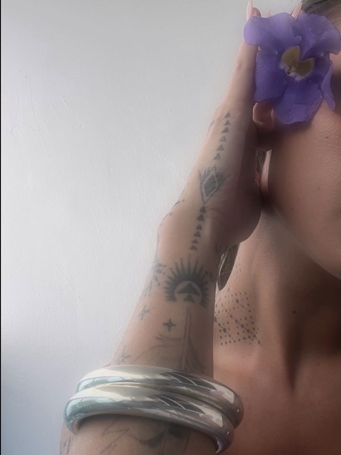 Tattooed arm with flower and silver bracelets