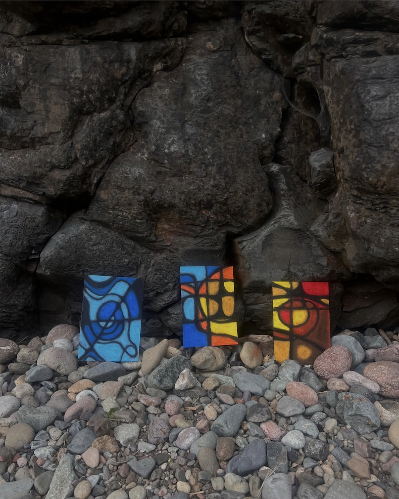 Colorful abstract paintings displayed on rocks at the shore